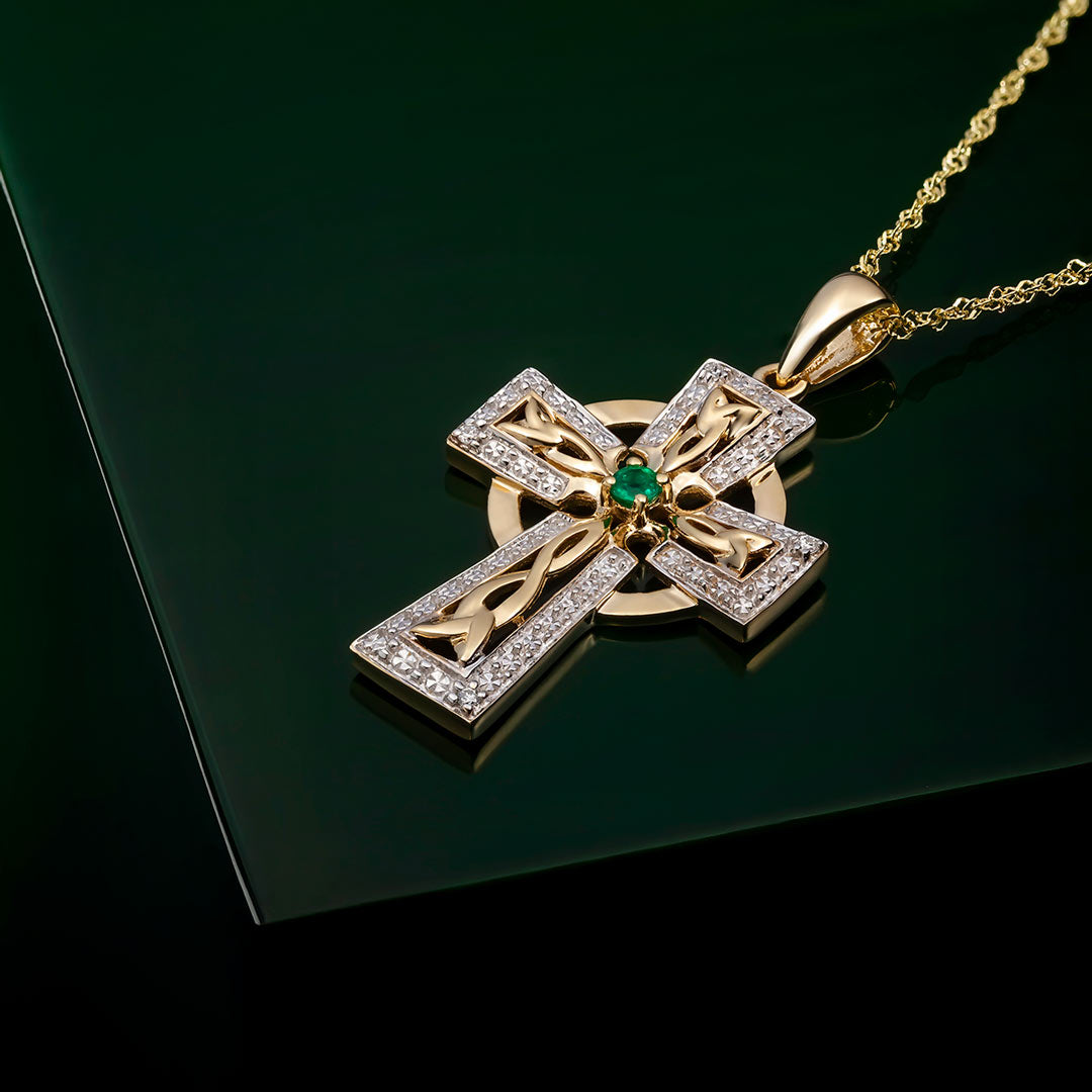 lifestyle image of gold celtic cross necklace on dark green background