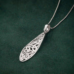 lifestyle image of celtic twist trinity knot pendant on dark green background