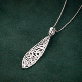 lifestyle image of celtic twist trinity knot pendant on dark green background