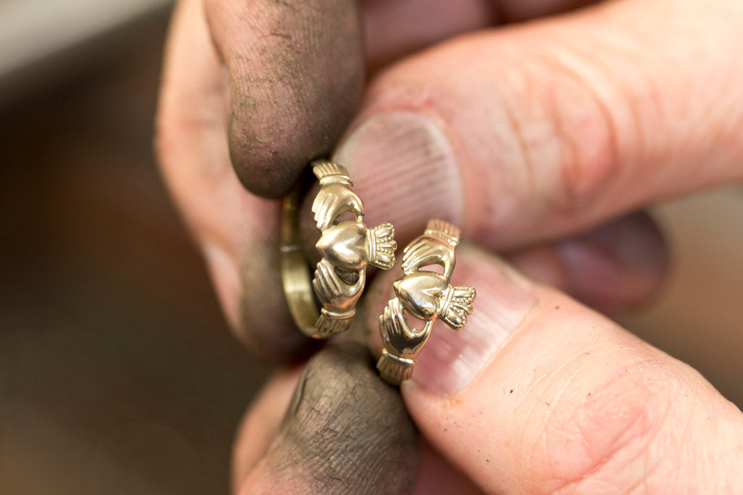 goldsmith holding two claddagh rings in his hands