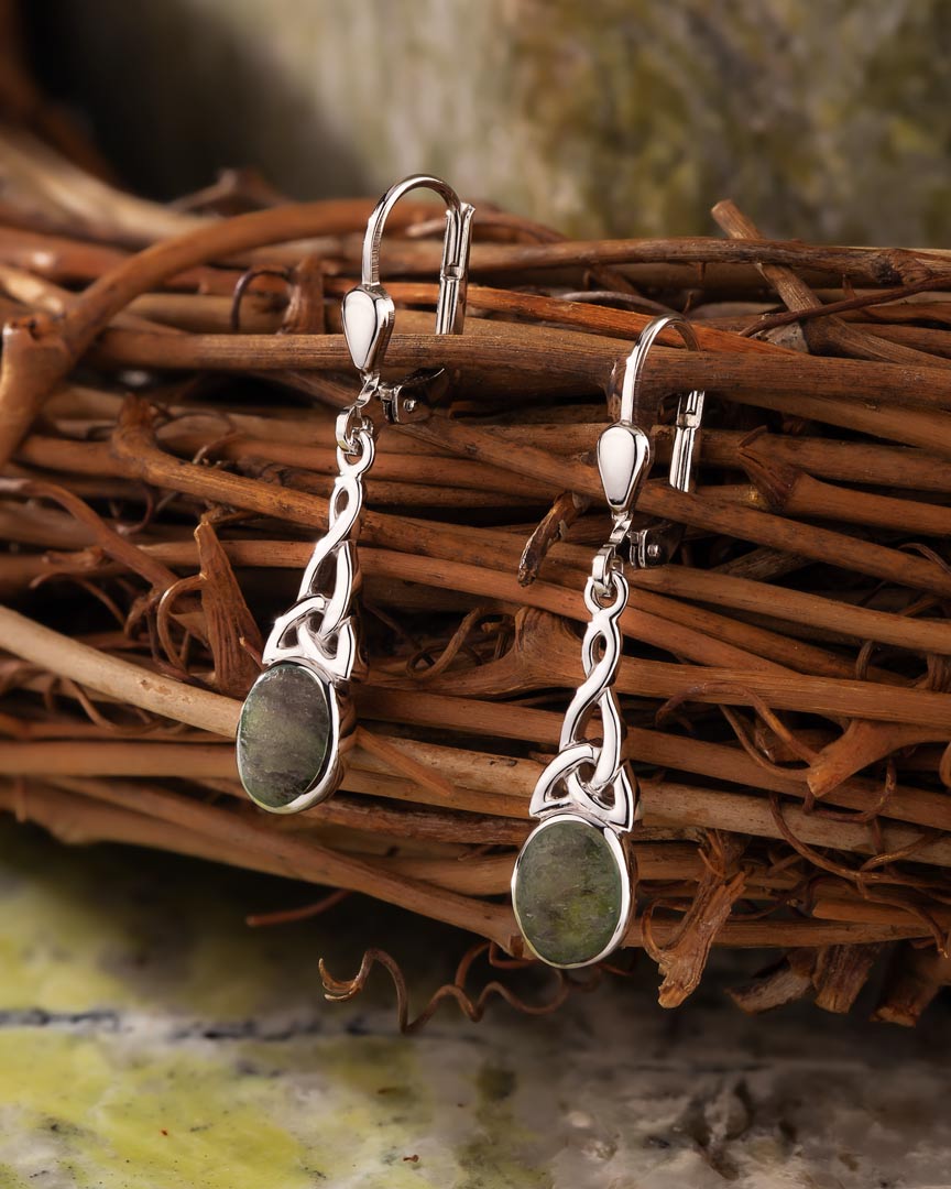 lifestyle image of  celtic drop earrings on green marble background