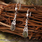 lifestyle image of  celtic drop earrings on green marble background