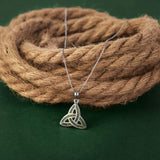 Silver Trinity knot pendant necklace on a rope against a green background