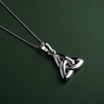 lifestyle image of double-sided trinity knot pendant on green background