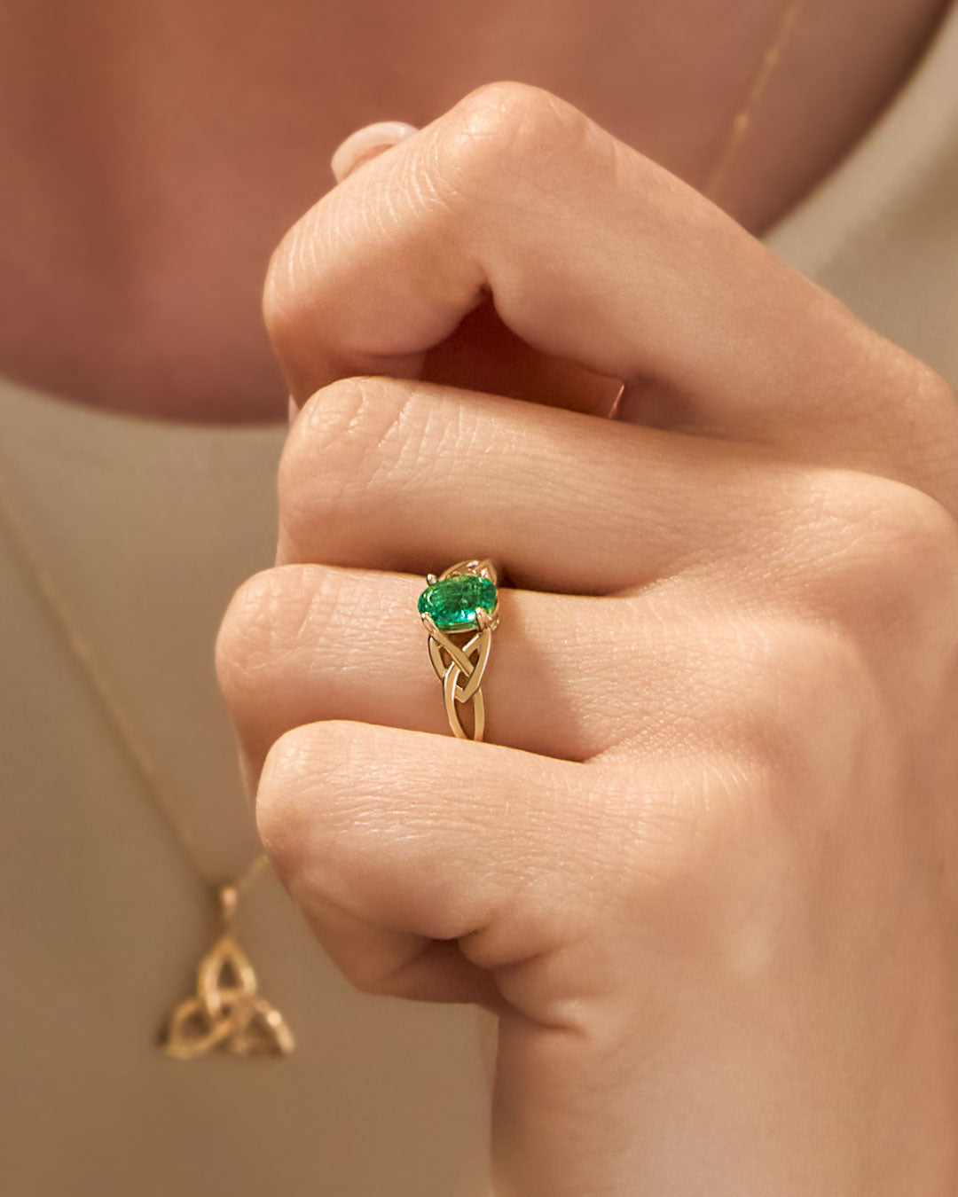 closeup image of yellow gold emerald Celtic Knot Ring on a model