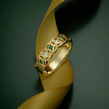 lifestyle image of gold diamond and emerald trinity knot ring band