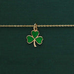 lifestyle image of  Solvar green enamelled gold shamrock necklace on green background