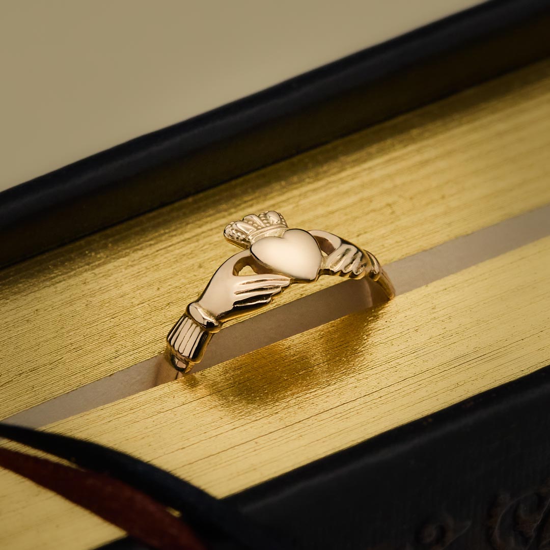 lifestyle image of ladies Gold Claddagh ring on a wooden surface
