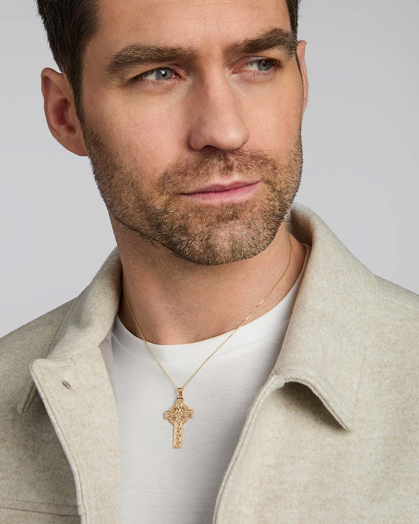 a male model wearing large yellow gold celtic cross pendant