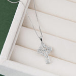 Silver cross pendant necklace on a white cushioned surface
