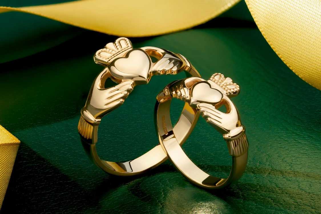 two gold claddagh rings presented on a styled background