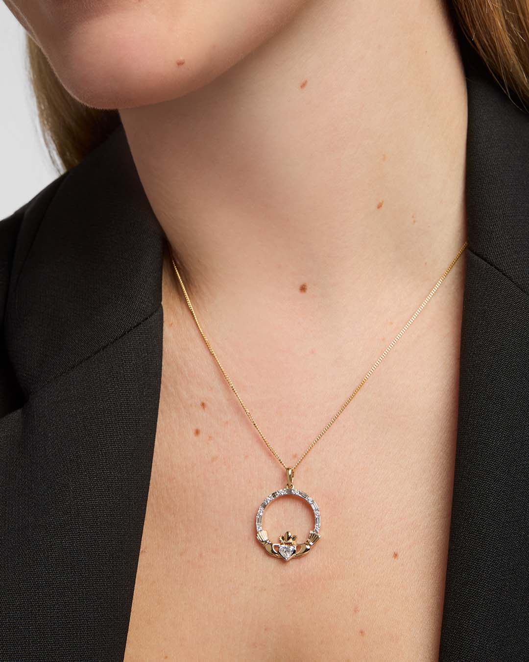 Close-up of a model showcasing a Solvar gold Claddagh necklace with a striking, large diamond set in the heart pendant.
