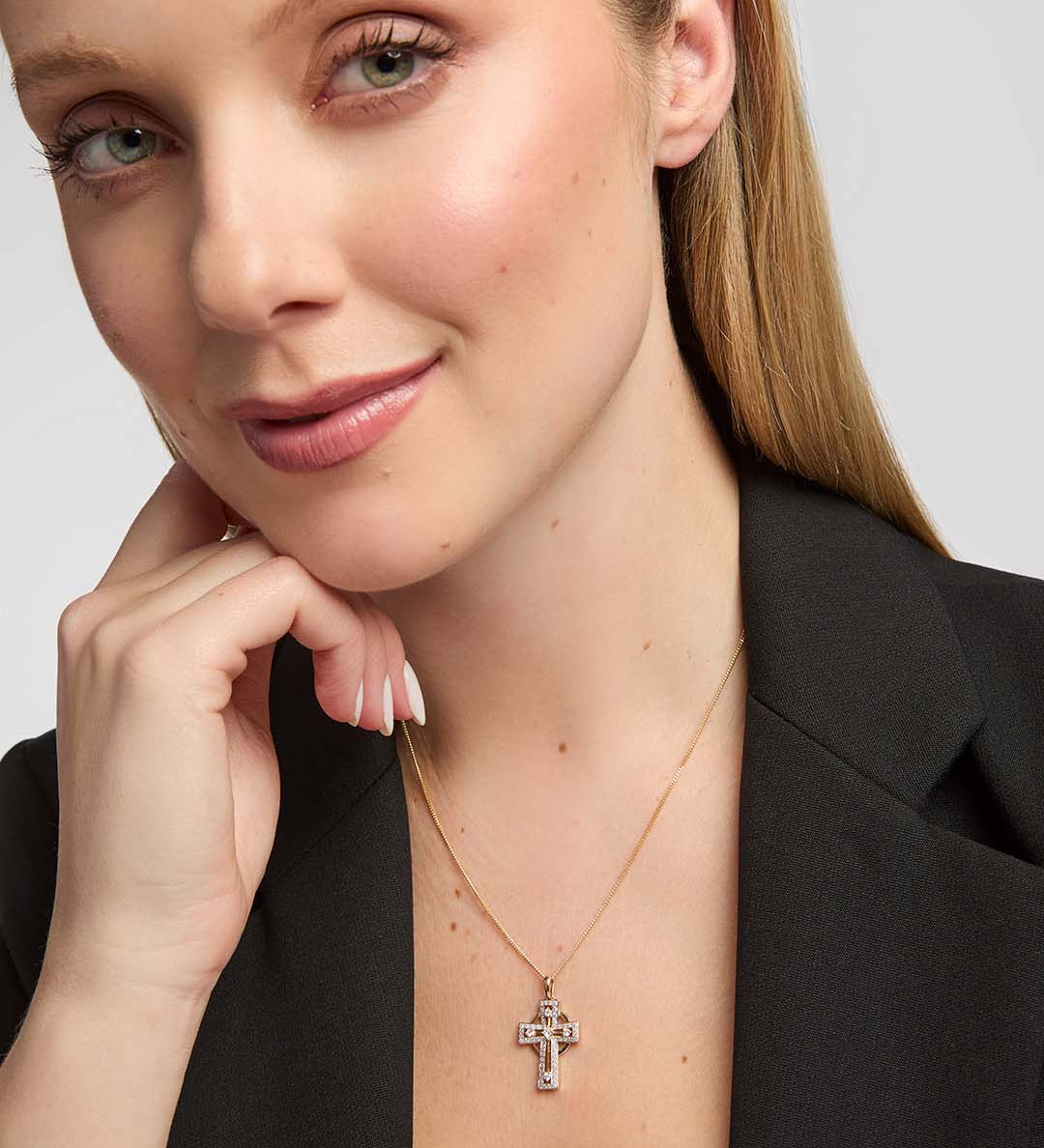 female model showcasing a delicate 14k gold diamond-set Celtic Cross pendant from Solvar