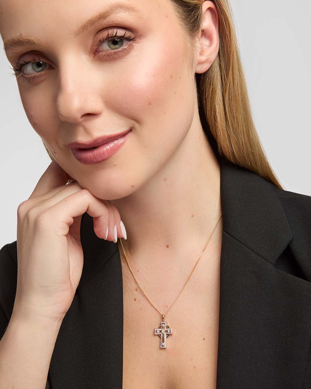 female model showcasing a delicate 14k gold diamond-set Celtic Cross pendant from Solvar
