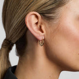 a model wearing gold claddagh creole small earrings