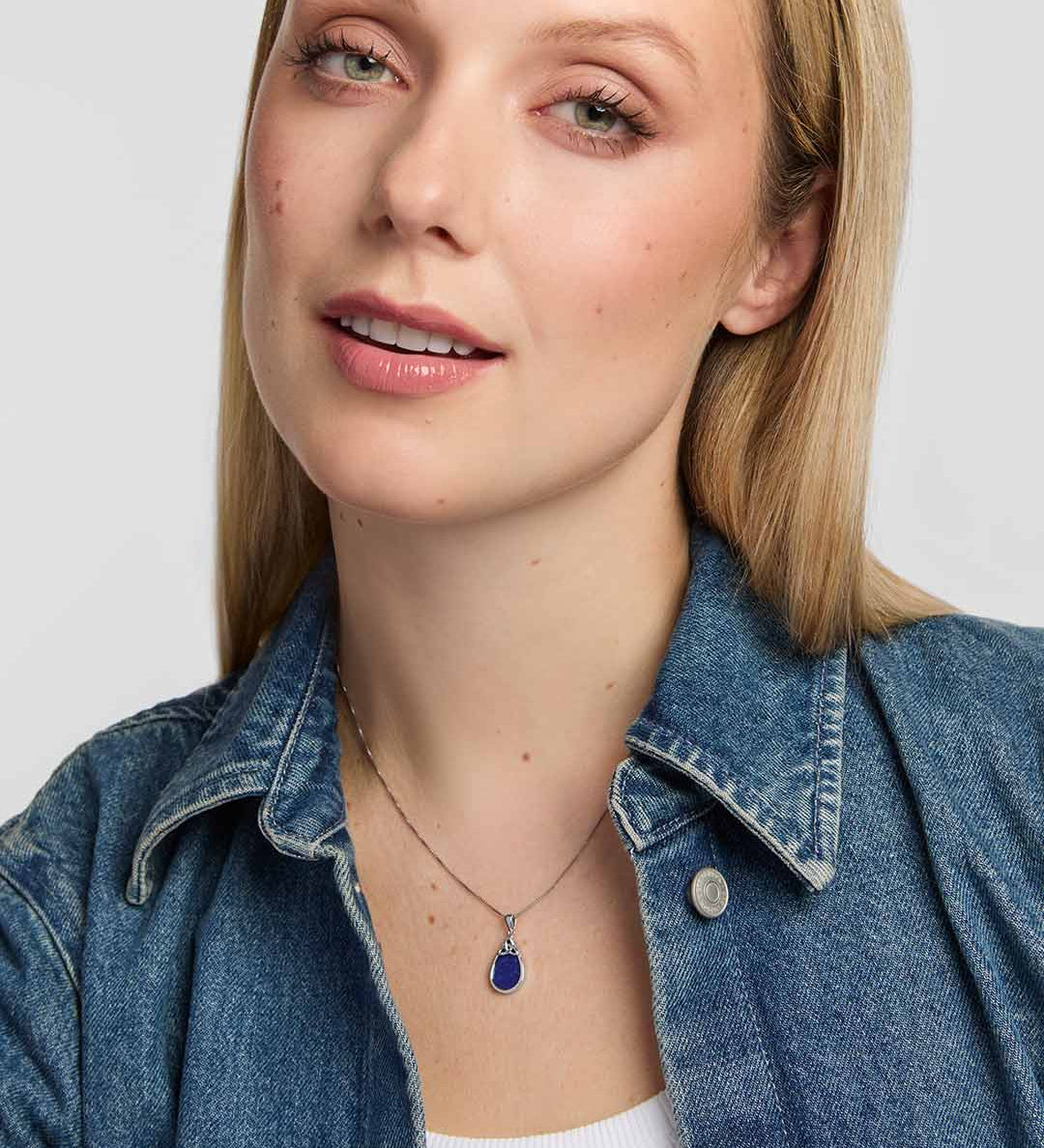 An elegant teardrop pendant with a rich blue lapis stone, polished silver surround and openwork Trinity Knot detail presented on a model