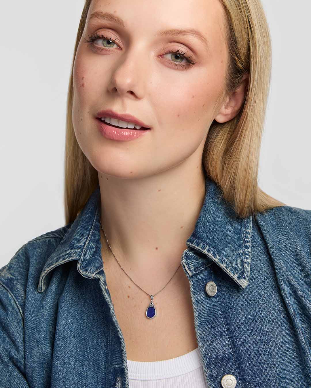 An elegant teardrop pendant with a rich blue lapis stone, polished silver surround and openwork Trinity Knot detail presented on a model