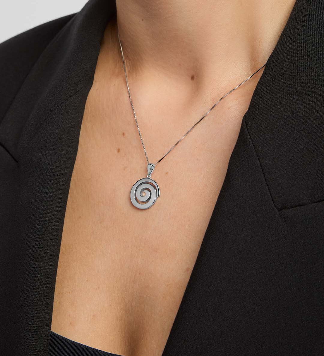 Silver Celtic spiral pendant necklace from Solvar on a person wearing a black blazer.