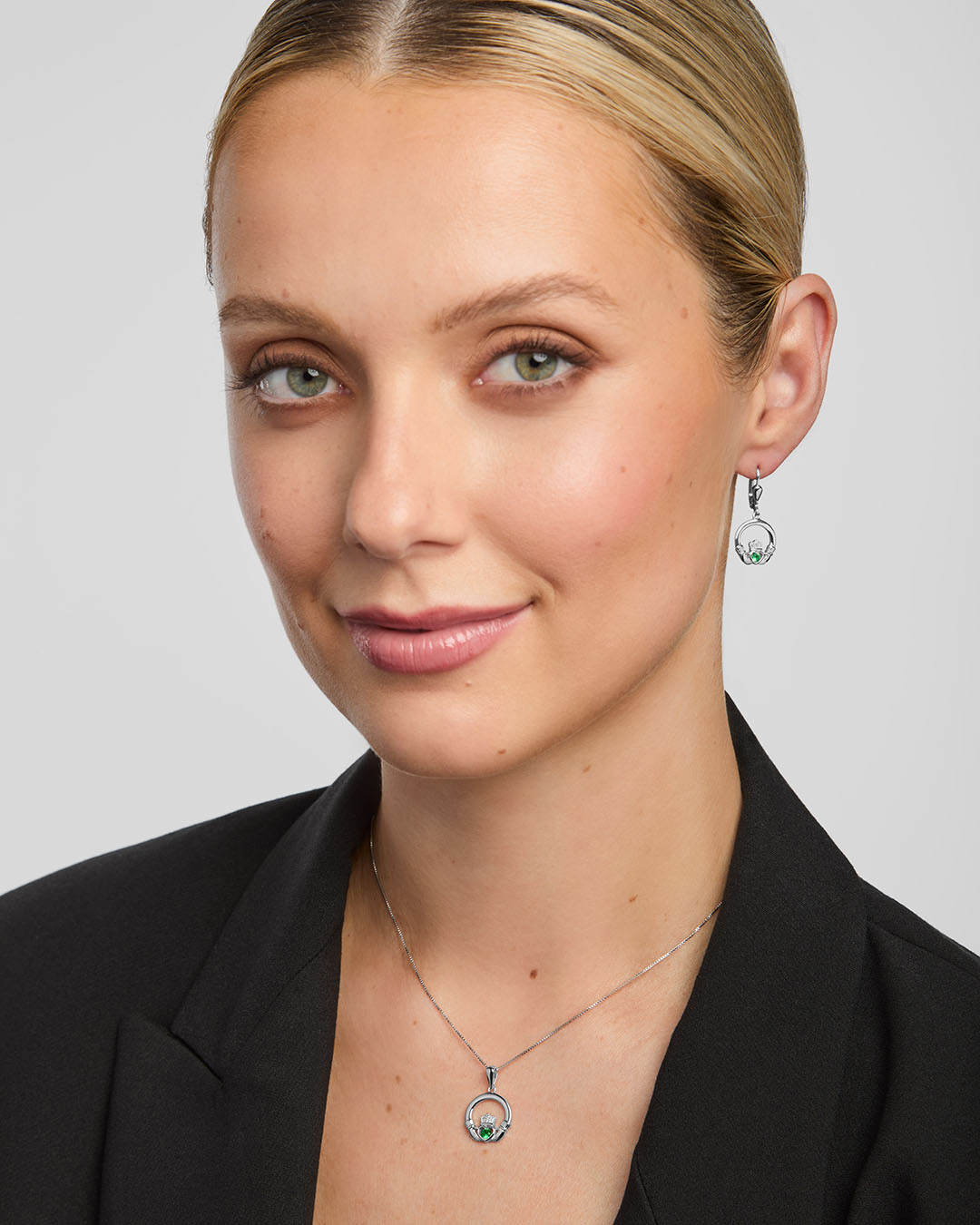 a female model wearing green crystal claddagh pendant and earrings