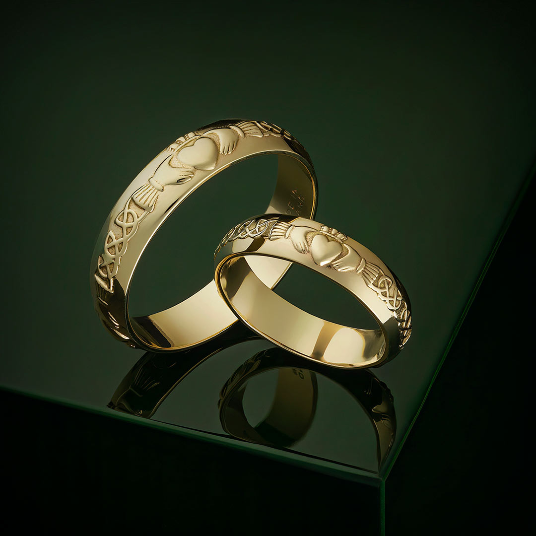 styled image of gold claddagh wedding bands on green background