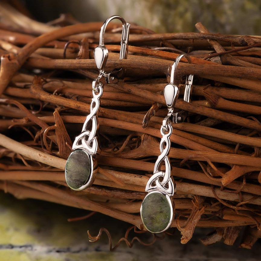 lifestyle image of  celtic drop earrings on green marble background