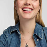 model wearing a polished silver Trinity Knot  pendant entwined around a circular green marble inlay, combining flowing Celtic lines with a clean, openwork finish.