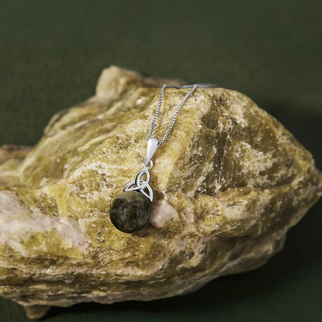 lifestyle image of Celtic Trinity Knot necklace with round green marble displayed on Connemara marble 