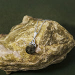 lifestyle image of Celtic Trinity Knot necklace with round green marble displayed on Connemara marble 