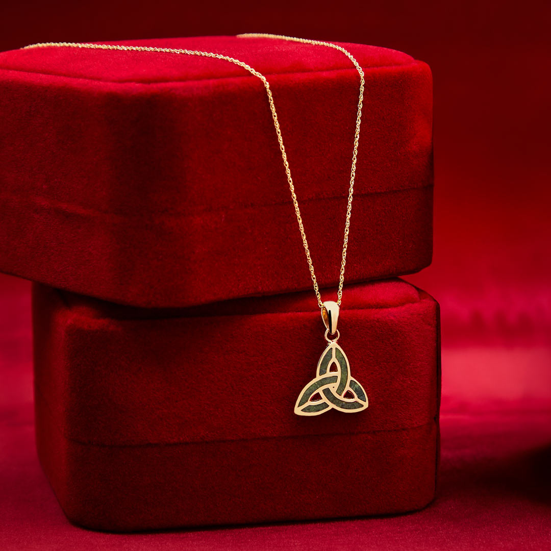 lifestyle image of connemara marble gold trinity knot necklace placed on red luxury box