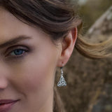Close-up of a female model wearing a green marble Trinity Knot earring with a blurred natural background