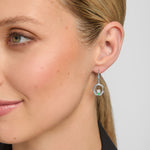 close-up image of a model wearing green crystal claddagh drop earrings in silver