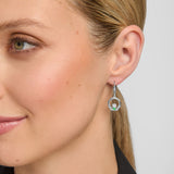 close-up image of a model wearing green crystal claddagh drop earrings in silver