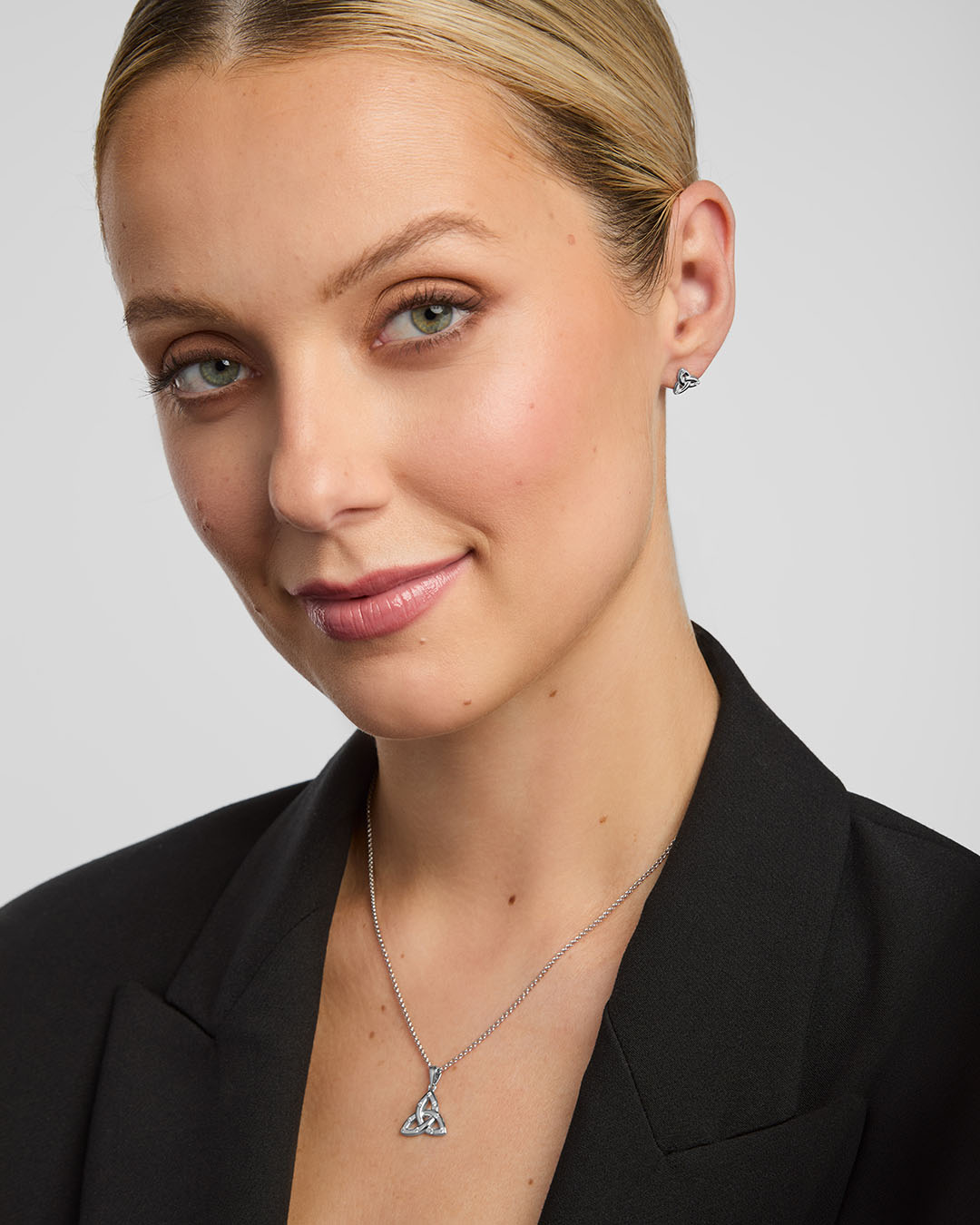 model wearing matching trinity knot earrings and pendant set in silver from Solvar Irish jewellery