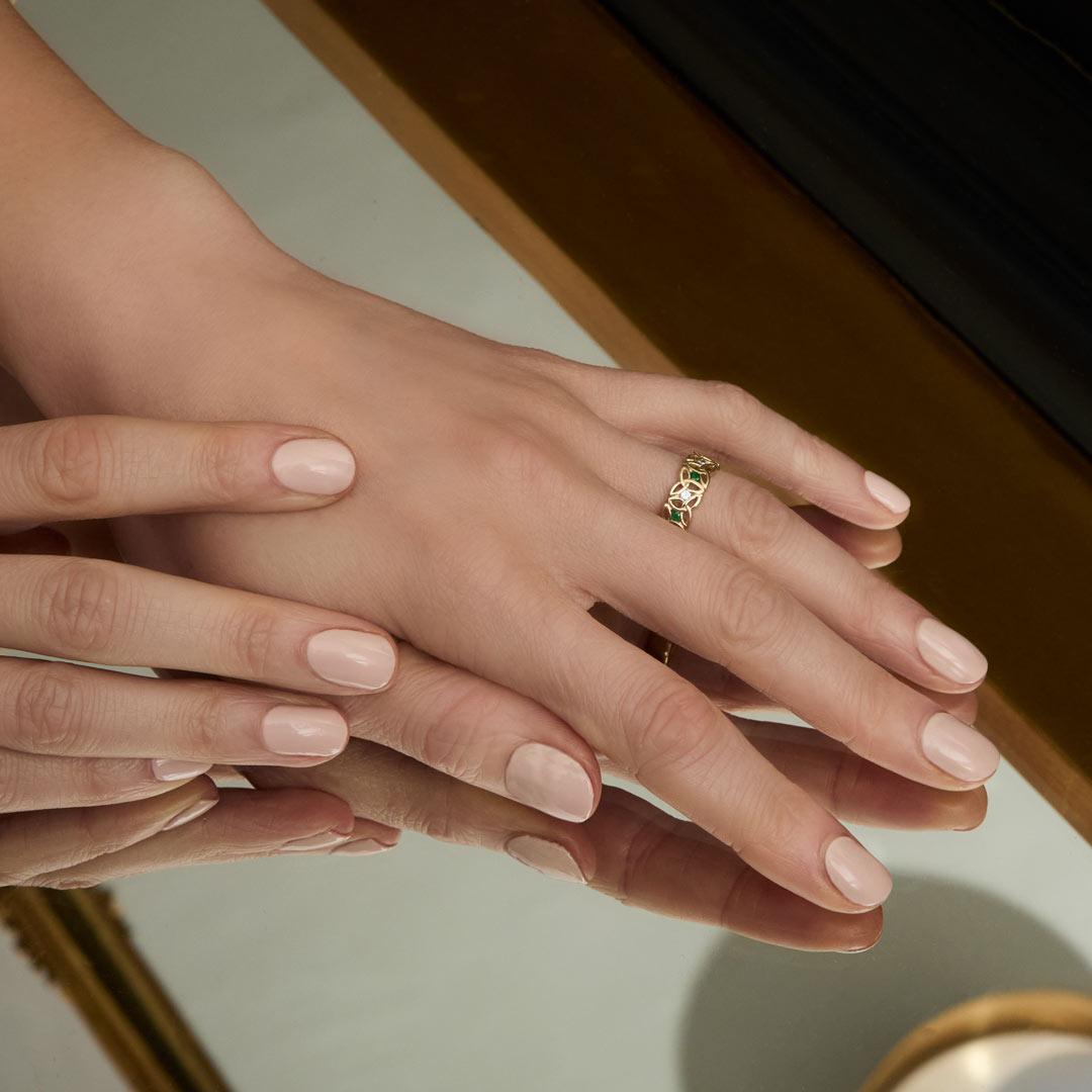 a model wearing yellow gold emerald and cz Trinity Knot band ring from Solvar