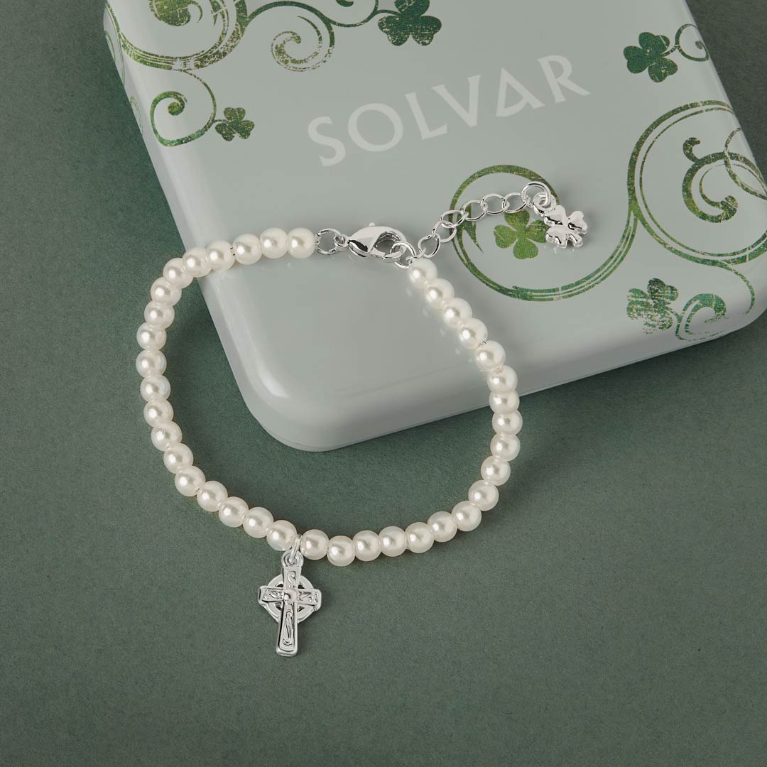 Celtic pearl bracelet with a silver Celtic cross charm on a green background