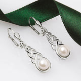 Silver Celtic Knot drop earrings with pearls on a white background with green ribbon