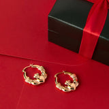 lifestyle image of Claddagh Hoop earrings in yellow gold on the red background