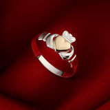 lifestyle image of gold hear Claddagh ring on red background