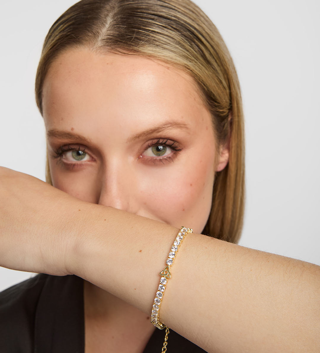 close-up image of gold plated trinity knot  celtic tennis bracelet on a woman's wrist