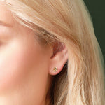 A model wearing Solvar tiny gold shamrock stud earrings