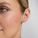 close-up image of gold shamrock stud earrings on a model