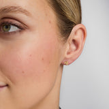 close-up image of gold shamrock stud earrings on a model