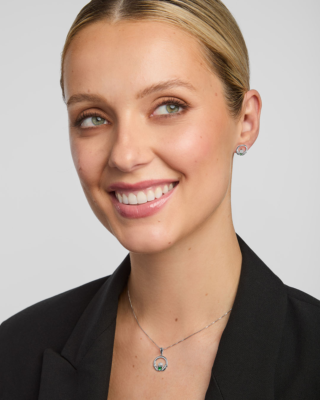 green crystal claddagh necklace and earrings set on a model