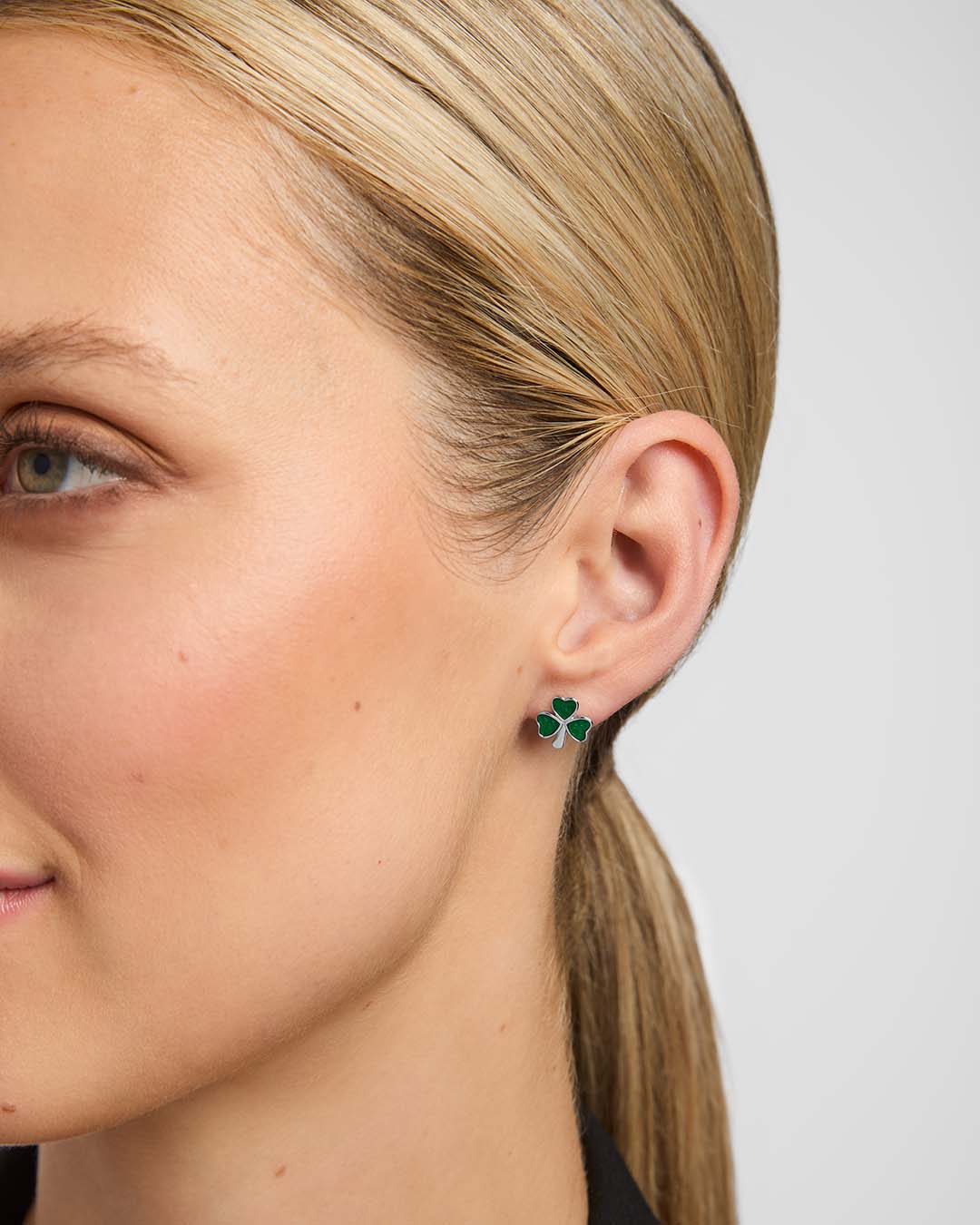 Close-up of a female model wearing green Shamrock stud earrings from Solvar