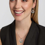 a female model wearing matching celtic Claddagh necklace and earrings with a green cubic zirconia Claddagh heart