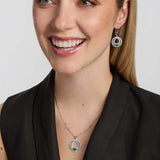 a female model wearing matching celtic Claddagh necklace and earrings with a green cubic zirconia Claddagh heart
