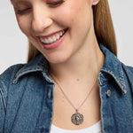 A close-up of a smiling woman wearing a Round Connemara marble and marcasite pendant with intricate interwoven Celtic knotwork design on a silver chain