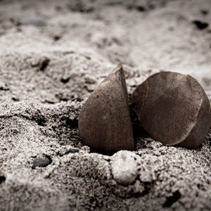 a stone split up in to parts on a sandy surface