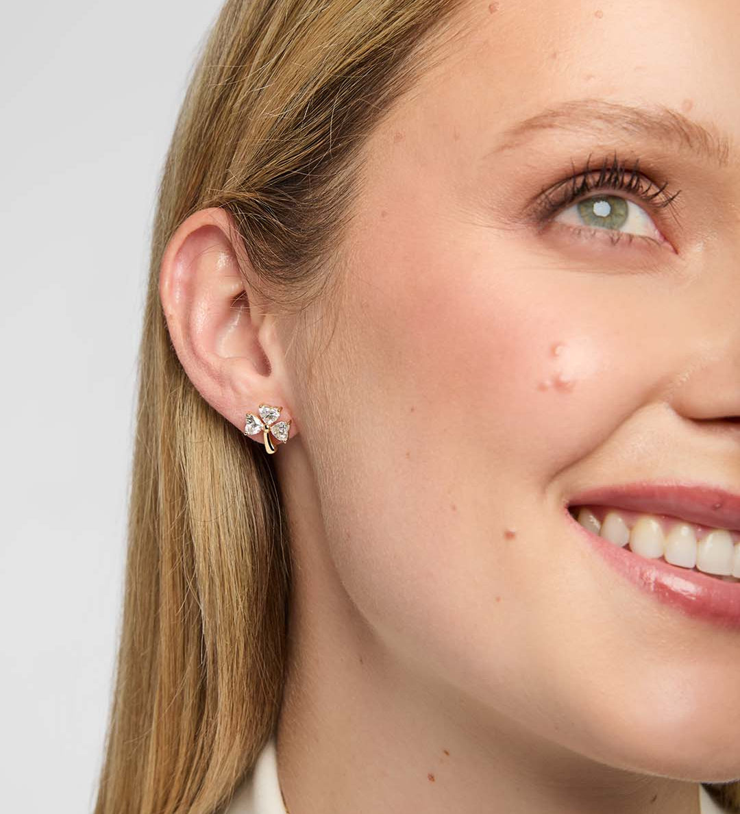 Close-up of model wearing gold Shamrock stud earring with lab-grown diamond