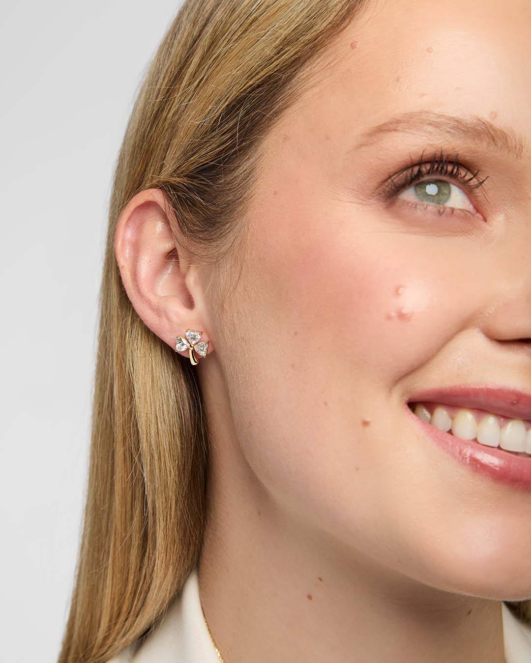 Close-up of model wearing gold Shamrock stud earring with lab-grown diamond